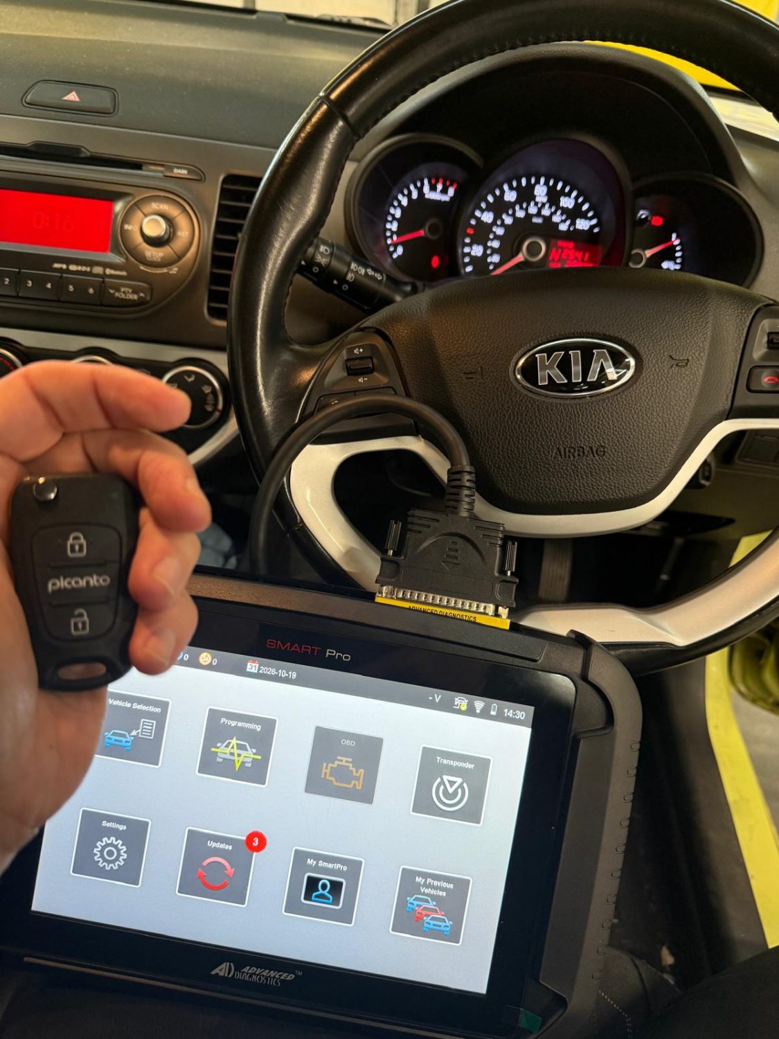 Mobile auto locksmith in Maidstone programming a replacement Kia key with diagnostic equipment plugged into the car
